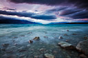 Evening colors appear in the sky over glacial blue Lake Pukaki. South Island, New Zealand.